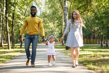 African American father and a white mother with a daughter on the walk.