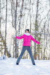Happy winter fun young girl playing throwing snow with arms up open in freedom enjoying the cold season