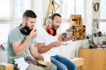 two worker in a carpenter's workshop taking a break