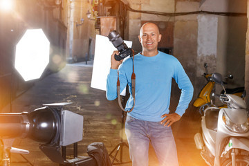 Photographer with camera among photo equipment