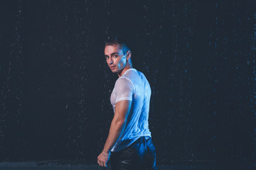 Fototapeta na wymiar Fresh portrait of muscular man with water splashes on dark background.