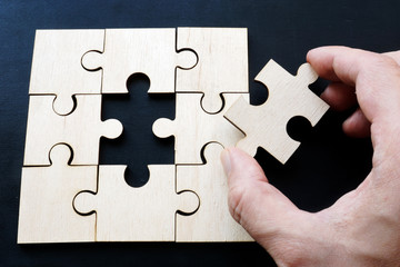 Hand is holding piece of jigsaw puzzle. Problem solving in business.