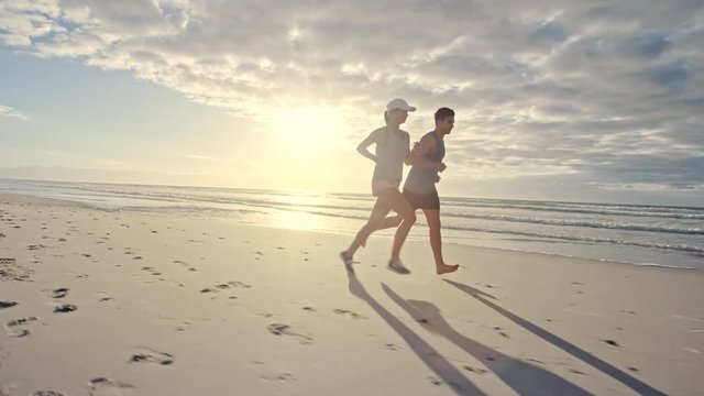 Couple running along the beach in morning