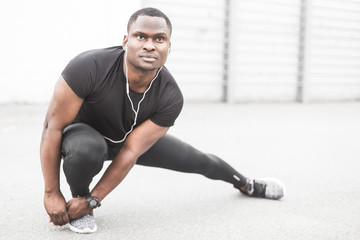 Obraz premium Young male jogger athlete training and doing workout outdoors in city. a black man resting after a workout and listening to music and watching a sports watch. free copyspace for text