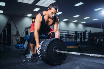 Obraz na płótnie Canvas Male powerlifter prepares a barbell in gym