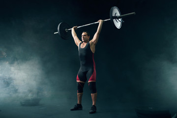 Strong weight lifter in sportswear takes a weight