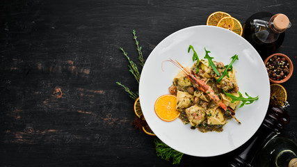 Ravioli with shrimp and seafood. Italian cuisine. Dumplings. In a plate on a wooden background. Top view. Free copy space.