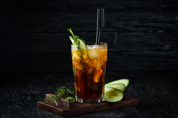 Tasty alcoholic cocktail. Cola, whiskey, cucumber and ice. On a wooden background. Top view.