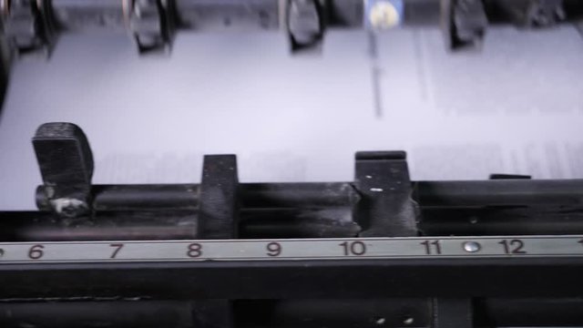 The work of a professional printing press in the printing house. The camera moves from right to left in slow motion. Offset printing machine.