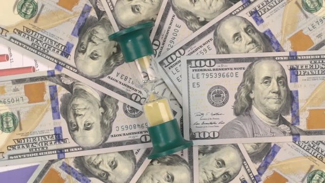 Rotation of the hourglass lying on the dollars.