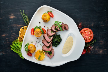 Veal steak with spinach and corn. On a wooden background. Top view. Free copy space