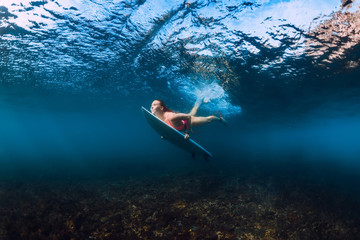 Sporty surfer woman dive underwater with under wave.