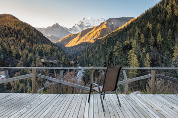 Chair on wooden balcony with valley in autumn at evening
