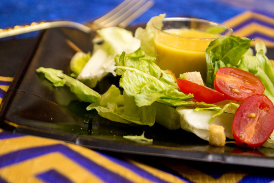 Lettuce salad set on plate with small cup of dressing