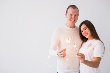 Romantic beautiful couple having date at Valentine's Day. Man and woman holding sparklers on white background with copy space