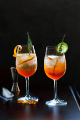Aperol Stpritz,alcoholic cocktail with ice cubes and slices of orange at black background. Classic Italian aperitif beverage with cocktail accessories