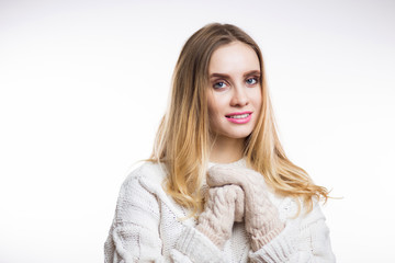 Naklejka premium Happy cheerful young woman wearing knitted warm beige sweater and mittens and looks at camera on white background