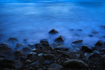 Obraz premium Long exposure image of Dramatic wave seascape with rock during twilight