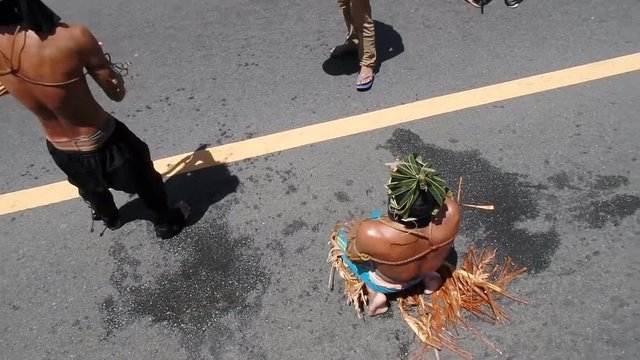 Unidentifiable maskedk penitent prone and lie prostrate on asphalt pavement beaten with bamboo stick imitating Christ&rsquo;s sufferings before crucifixion during Lenten week