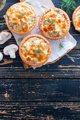Homemade savory autumn tarts with fresh seasonal mushrooms in a crisp pastry base on gray background