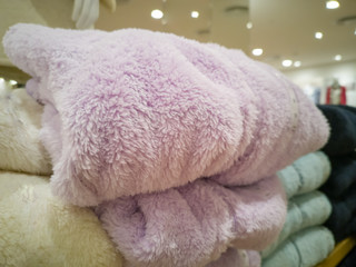 Sweater, many colors folded stacked on the floor. In the mall,soft focus.