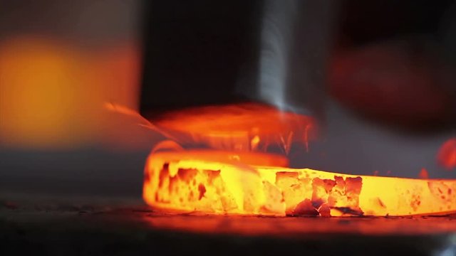 4k footage of forging hot iron on anvil with close up view. The smith forging iron on anvil with a hammer. Close up view of hot iron forging in workshop by the craftsman.