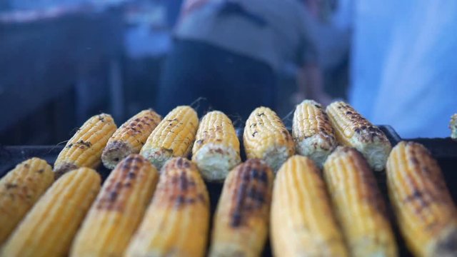 Close up of appetizing grilled sweet corn on the bbq grill. Street food festival.