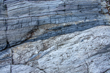 Gray stone wall with stripes of geological processes.