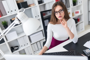 A young girl sitting at a table and typing on the keyboard.