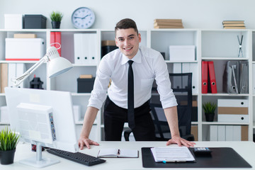 A young man stands in the office and put his hands on the table. © Ivan Traimak