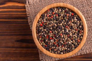 Mix of peppers in bowl burlap napkin on wooden background