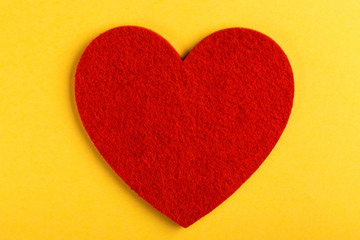 Red felt heart on bright yellow background. St. Valentine's day