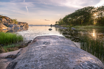 Rocks and trees reflected on sunset time. Finland archipelago.