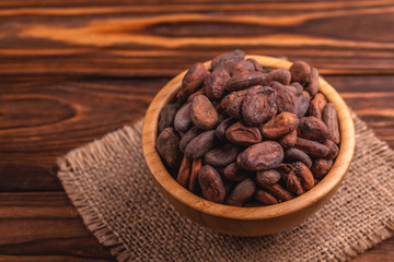 Bowl full of aromatic raw cocoa beans with burlap napkin