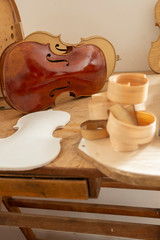 Template for Cello and wood shaving curls on table, and finished Cello or, violoncello, in...