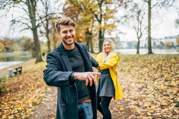 young couple having fun outdoors in autumn park, fall. Loughing and romp around