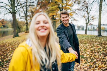 Fototapeta premium young couple having fun outdoors in autumn park, fall. Loughing and romp around
