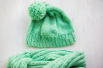 Female knitted hat and snood. Set of women winter cap and scarf on white wooden background. Female winter accessories. selective focus.