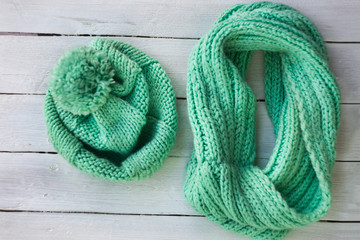 Female knitted hat and snood. Set of women winter cap and scarf on white wooden background. Female winter accessories. selective focus.