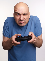 Angry bald man plays computer game isolated on grey studio background