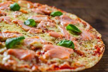 Pizza with Mozzarella cheese, salmon fish, tomato sauce. Italian pizza on wooden table background