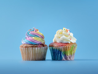Colorful and enteresting cupcake isolated on blue background studio close up shot.