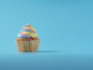 Colorful and enteresting cupcake isolated on blue background studio close up shot.