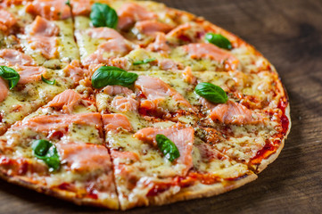 Pizza with Mozzarella cheese, salmon fish, tomato sauce. Italian pizza on wooden table background