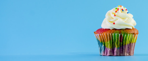 Colorful and enteresting cupcake isolated on blue background studio close up shot.