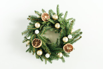 Christmas, New Year wreath frame made of fir branches decorated with dried oranges and Christmas balls on white background. Flat lay, top view blog hero header.