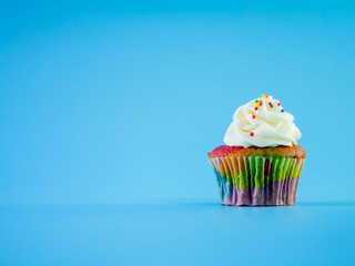 Colorful and enteresting cupcake isolated on blue background studio close up shot.