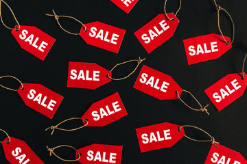 Black Friday sales discount composition. Red tags with word SALE on black background. Flat lay, top view.