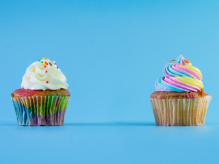 Colorful and enteresting cupcake isolated on blue background studio close up shot.