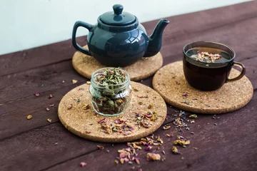 Foto op Aluminium a small blue teapot, a mug of tea and dry herbal tea on a wooden background. Herbal medicine. tea from flowers. © ritiniya